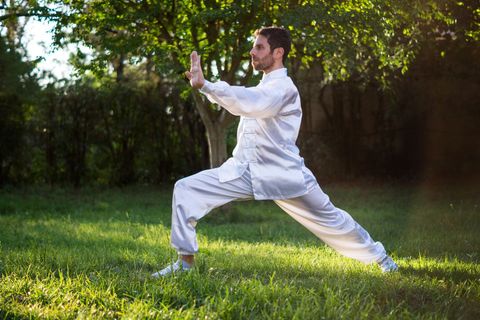 Man in karate dress standing on the grass during daytime