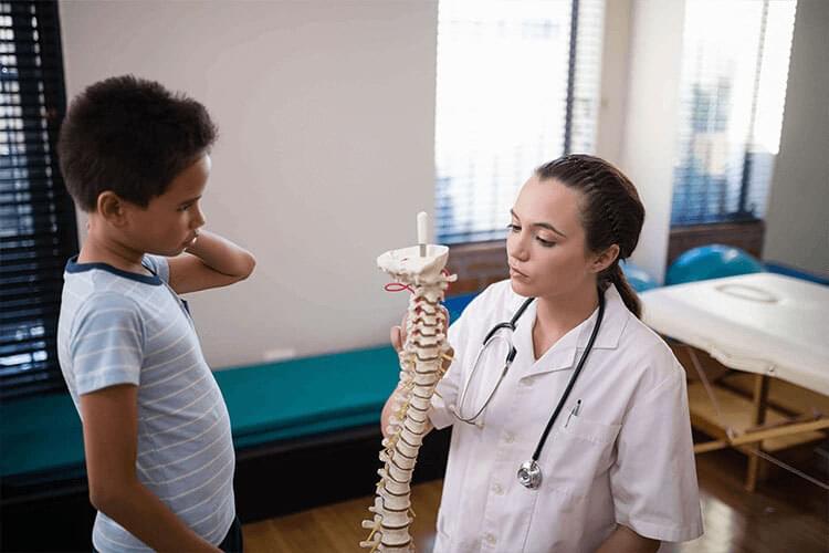 A chiropractor explaining to a children about chiropractic care.