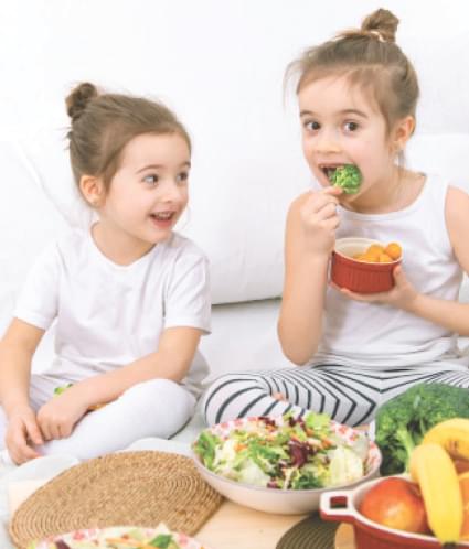 two young children building healthy habits eating vegetables and fruits
